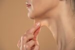 Woman pulling at loose skin under her chin and in her neck