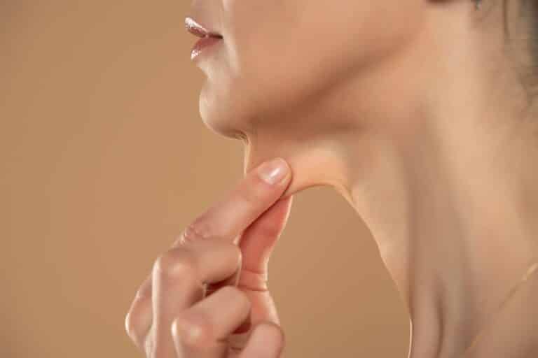 Woman pulling at loose skin under her chin and in her neck