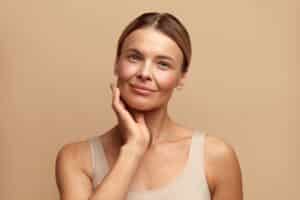 Attractive smiling woman touches her face after a skin tightening treatment