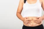 After Ozempic weight loss, young woman holds her belly skin and considers body contouring