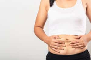 After Ozempic weight loss, young woman holds her belly skin and considers body contouring
